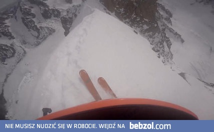 Narciarz zjeżdża wzdłuż szczytu w górach