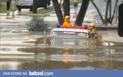 Wóz strażacki przejeżdża przez zalaną drogę 