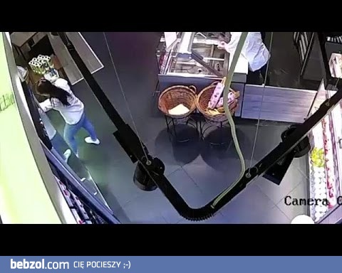 Ekspedientka próbuje ściągnąć wino z górnej półki